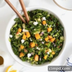 Vibrant Kale and Brussels Sprouts Salad 12 A large white serving bowl of kale salad with wooden salad spoons sticking out.