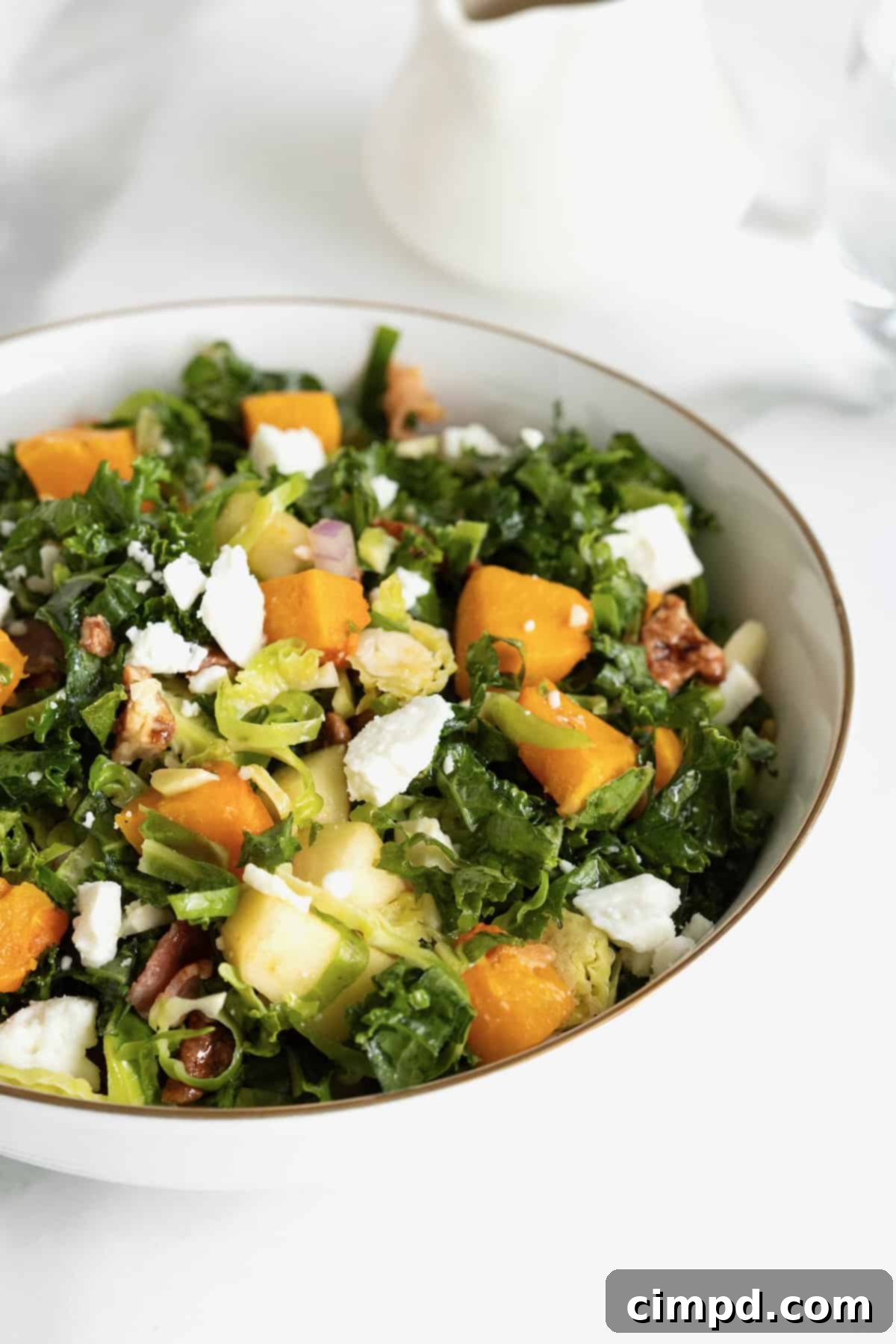 Vibrant Kale and Brussels Sprouts Salad 3 A gold-rimmed white salad bowl filled with kale and Brussels sprouts salad.