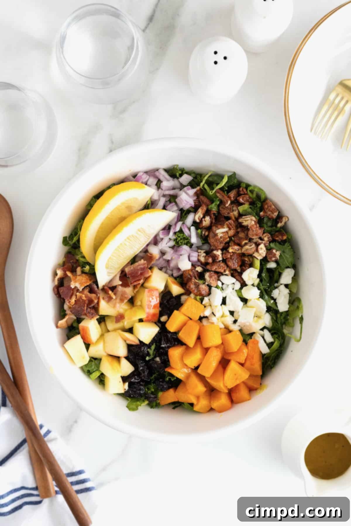 Vibrant Kale and Brussels Sprouts Salad 4 A large white serving bowl of kale salad with chunks of sweet potato, apple, feta cheese and bacon.