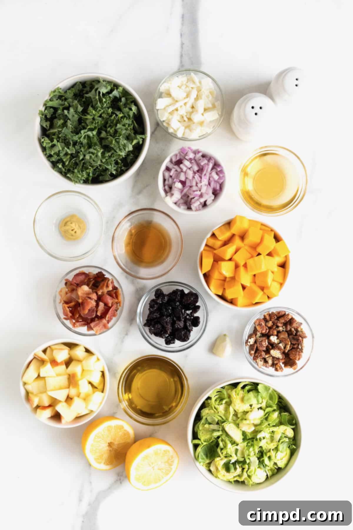 Vibrant Kale and Brussels Sprouts Salad 6 Ingredients to make Kale and Brussels Sprouts Salad in small glass bowls on a white marble counter.