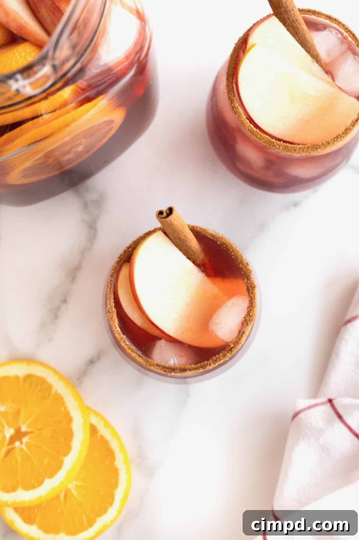 Spiced Apple Cider Sangria 11 A single glass of apple cider sangria, elegantly garnished with apple slices and a cinnamon stick, inviting a refreshing sip.