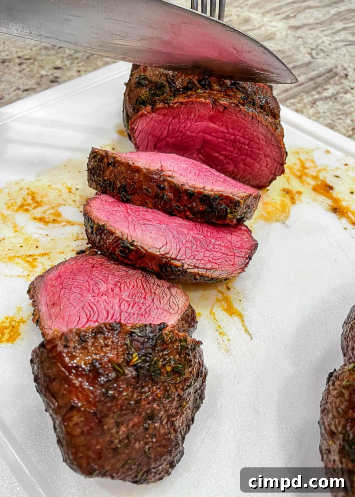 Slicing a roasted beef tenderloin for serving on a cutting board
