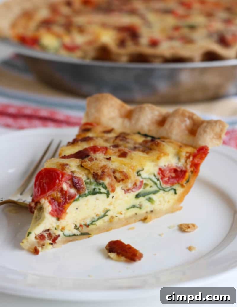 A delicious BLT Quiche, baked in a golden, flaky crust, revealing its rich filling of bacon, spinach, tomatoes, and white cheddar cheese.