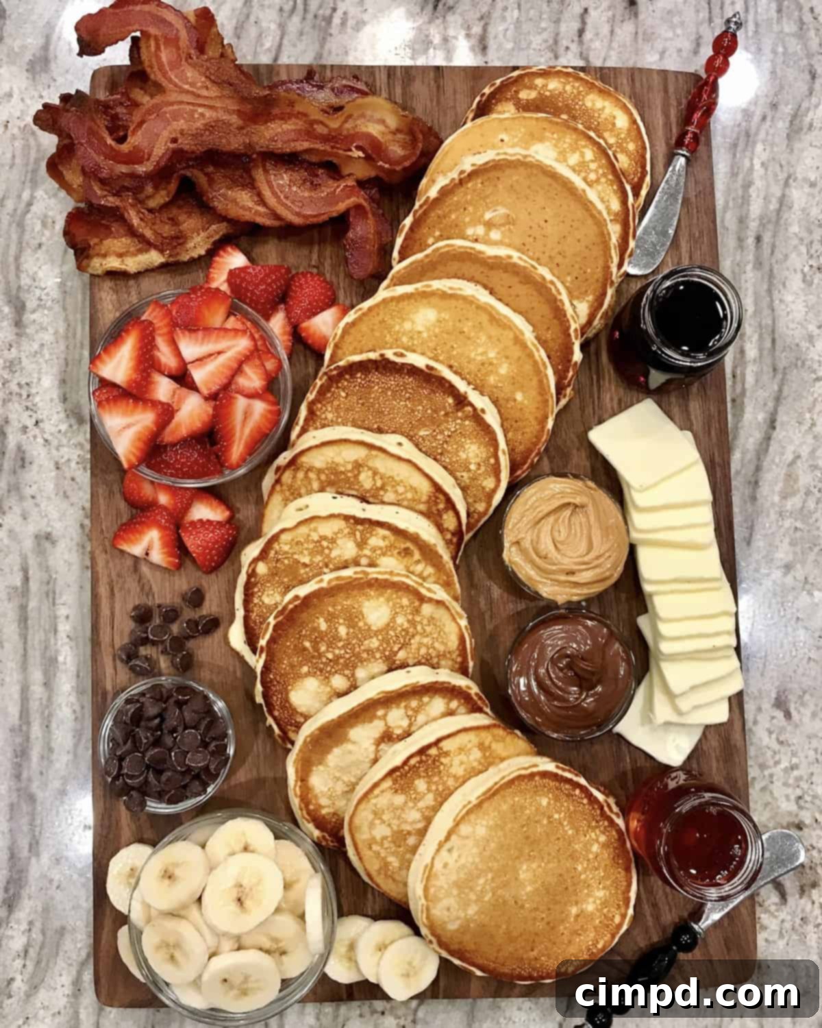 A festive Pancake Board, piled high with fluffy buttermilk pancakes and surrounded by an impressive variety of colorful toppings and delicious side dishes.