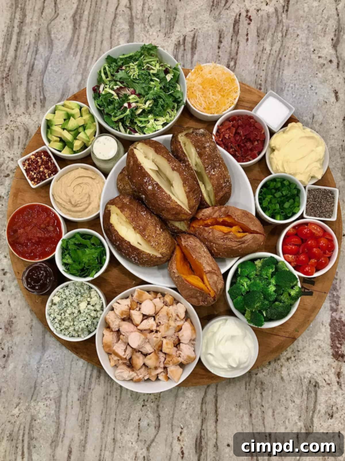 A beautifully arranged Build-Your-Own Baked Potato Board by The BakerMama, showcasing various toppings.