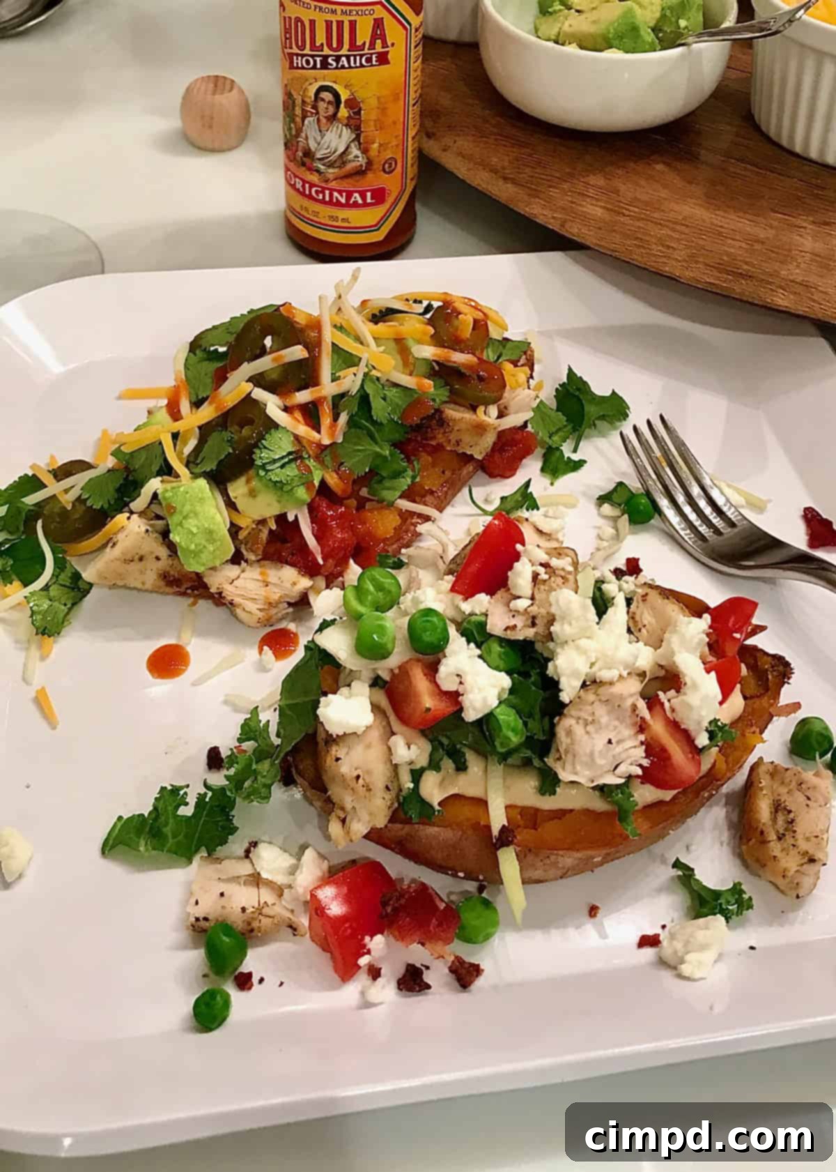 A hand holding a loaded baked potato over the Build Your Own Potato Bar by The BakerMama.