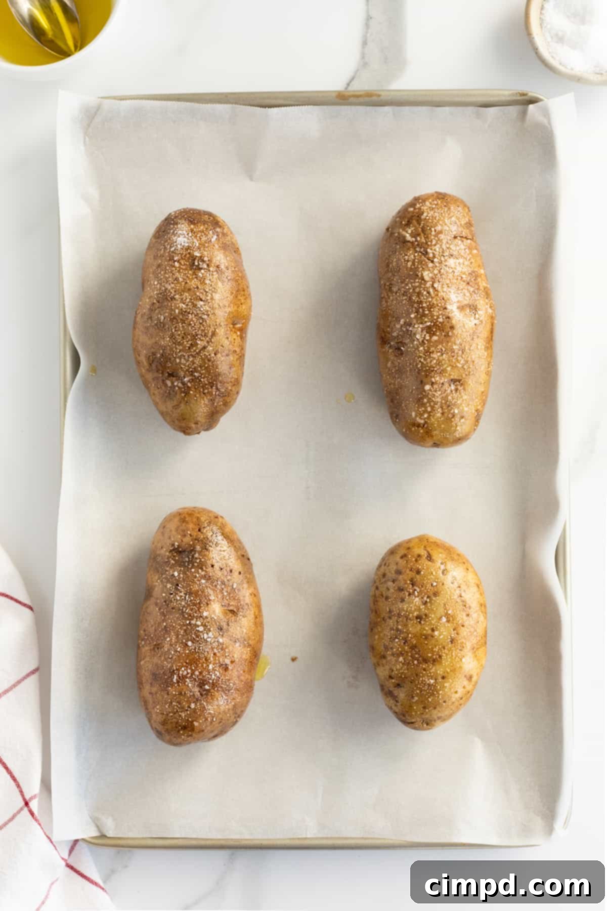 Seasoned potatoes arranged on a baking sheet with a wire rack, ready for the oven, by The BakerMama.