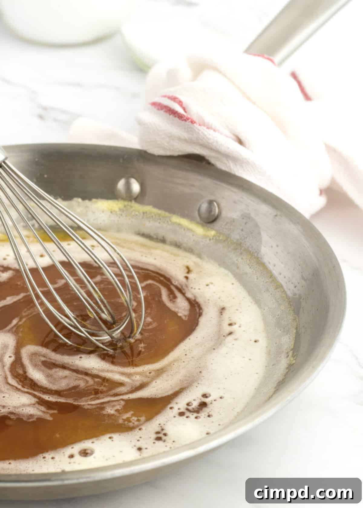 A perfectly prepared bowl of brown butter, showcasing its golden color and frothy texture, ready to be used in various recipes by The BakerMama.