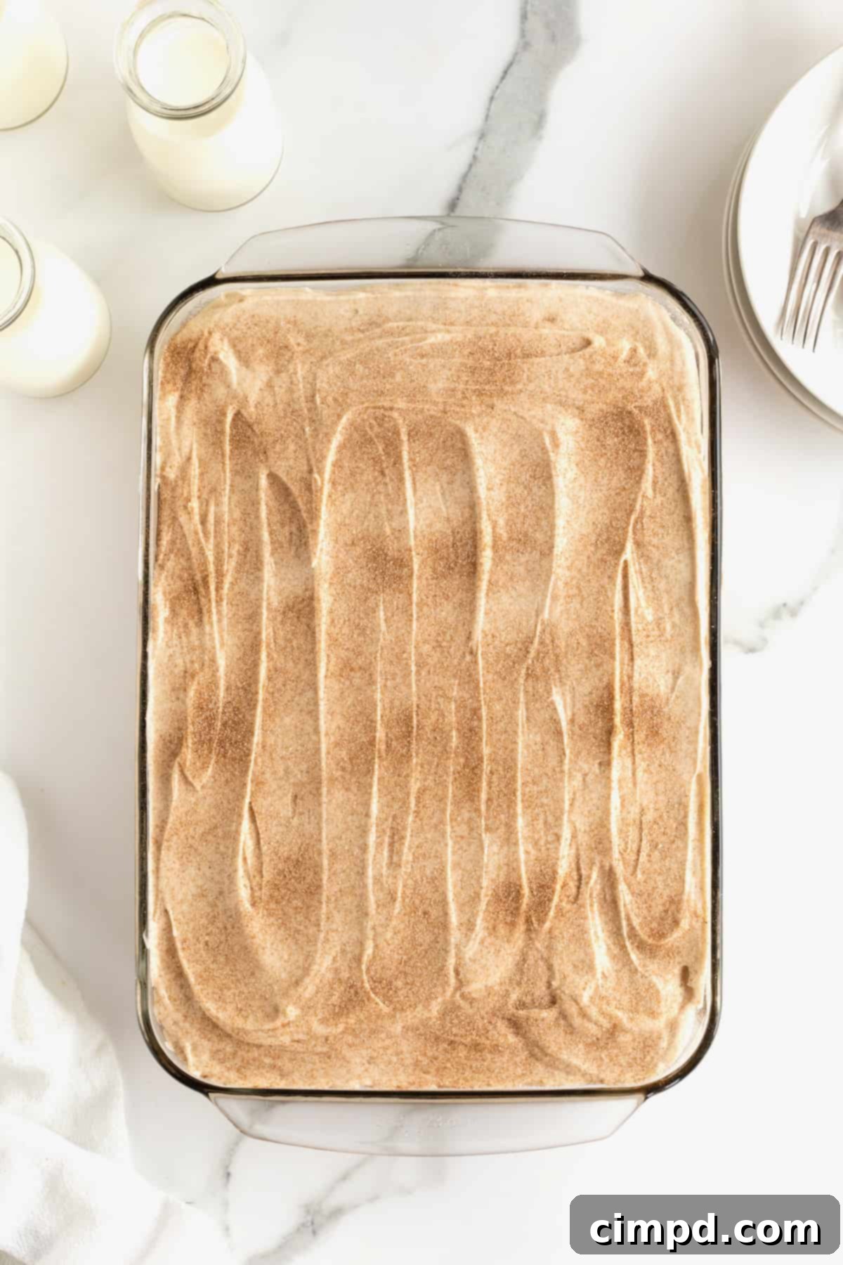 A beautifully frosted zucchini cake, generously sprinkled with cinnamon sugar on top, ready for serving.