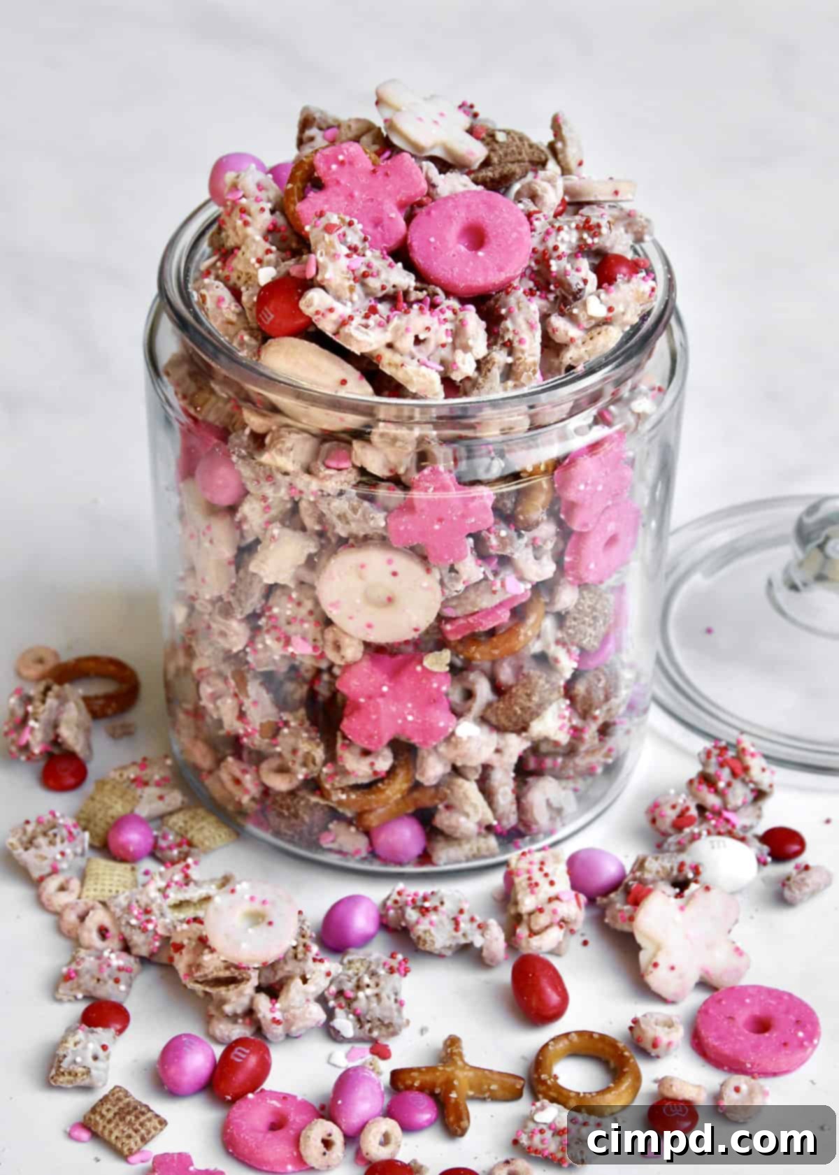 A close-up shot of the diverse range of ingredients for XOXO Valentine's Day Snack Mix, showcasing various cereals, pretzels, candies, and sprinkles in festive colors.