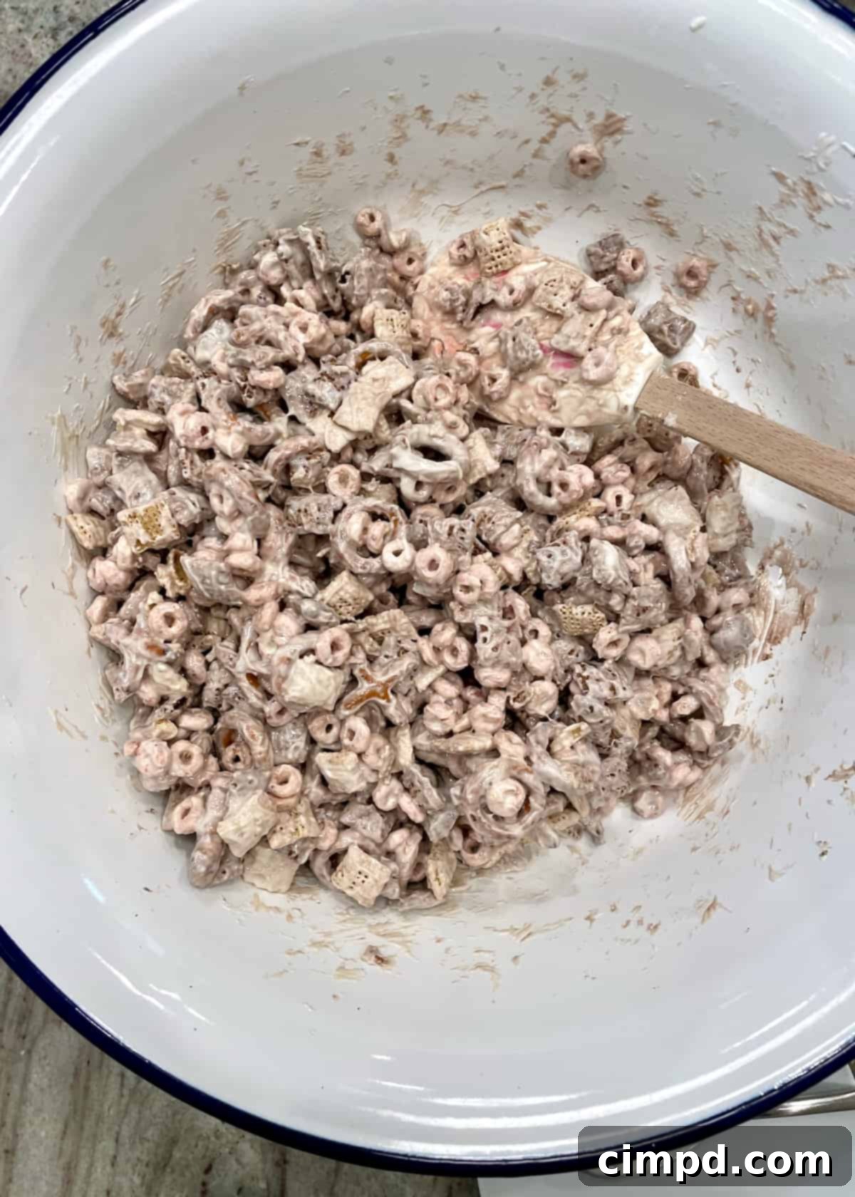 XOXO Valentine's Day Snack Mix coated with vanilla candy and sprinkled, spread on a baking sheet lined with parchment paper.