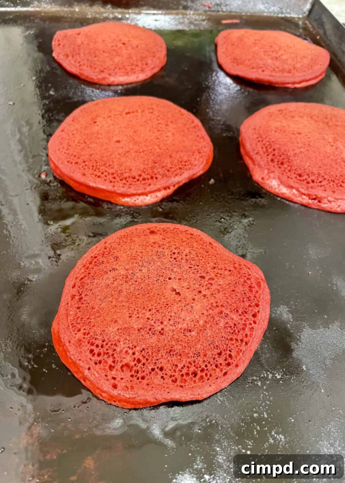 Love Day Pancake Brunch Board 5 Fluffy pink pancakes cooking on a griddle, ready to be flipped.