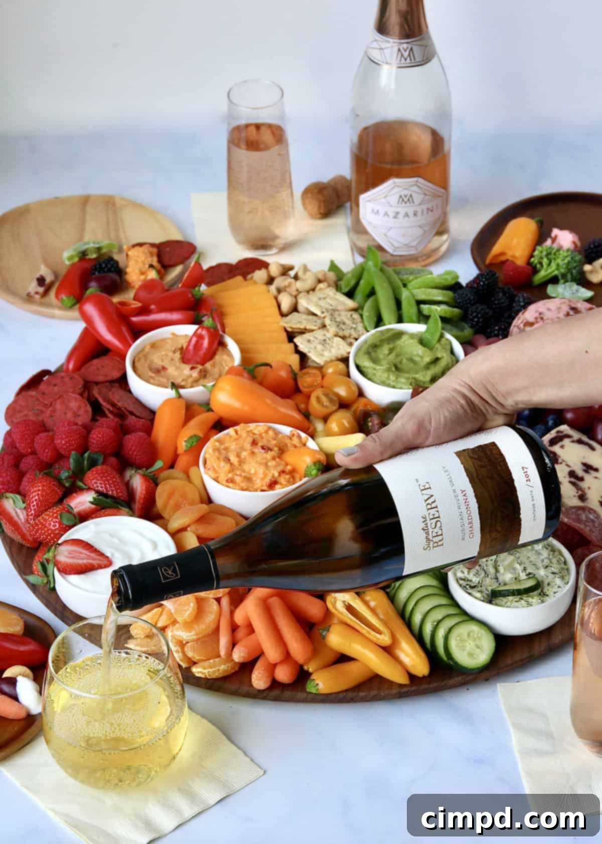 Wine bottles and glasses alongside the Eat the Rainbow Snack Board, suggesting perfect pairings.