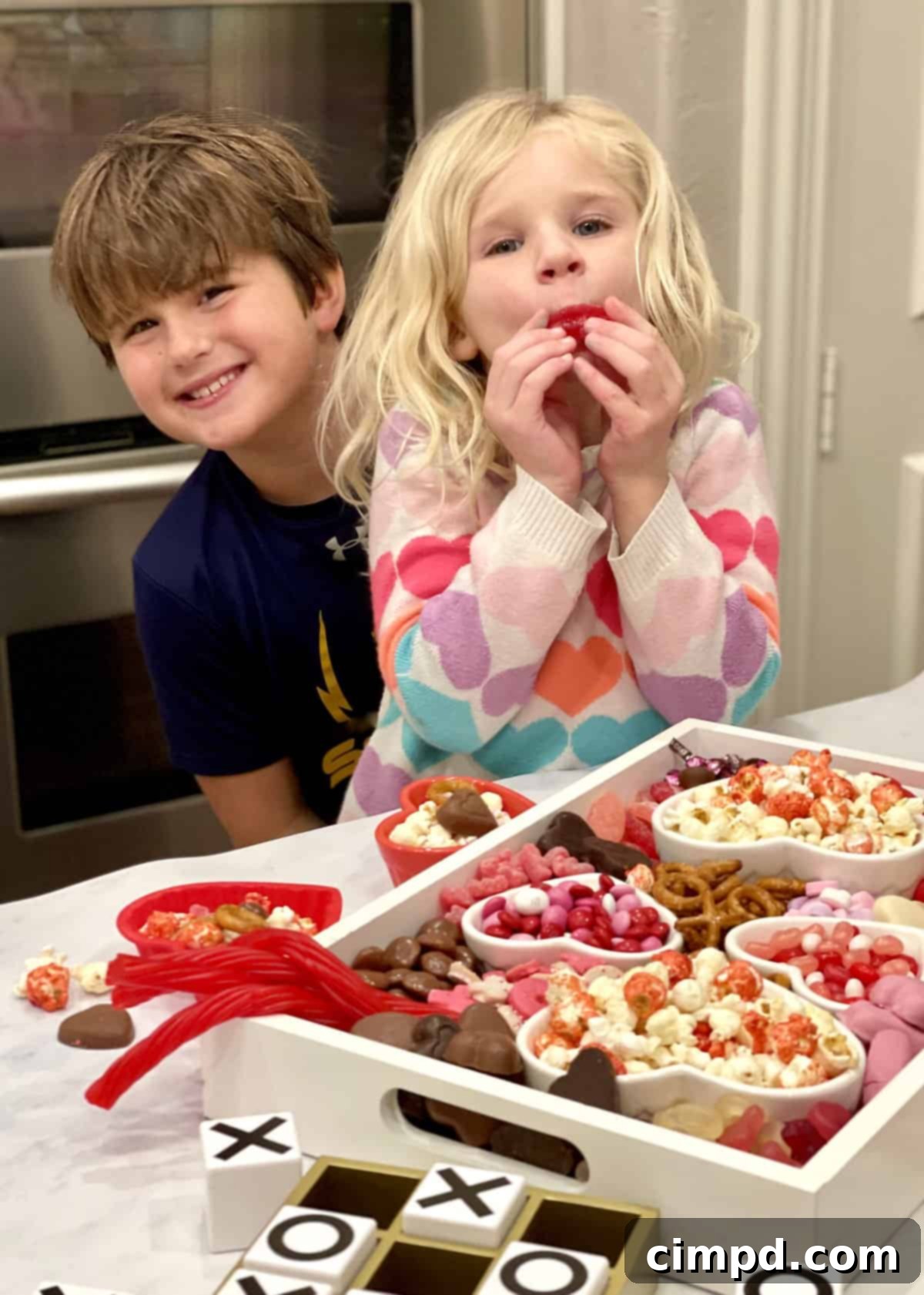 Close-up of a child's hand reaching for a treat on the Valentine's Day Movie Night Snack Board, highlighting family interaction and fun.