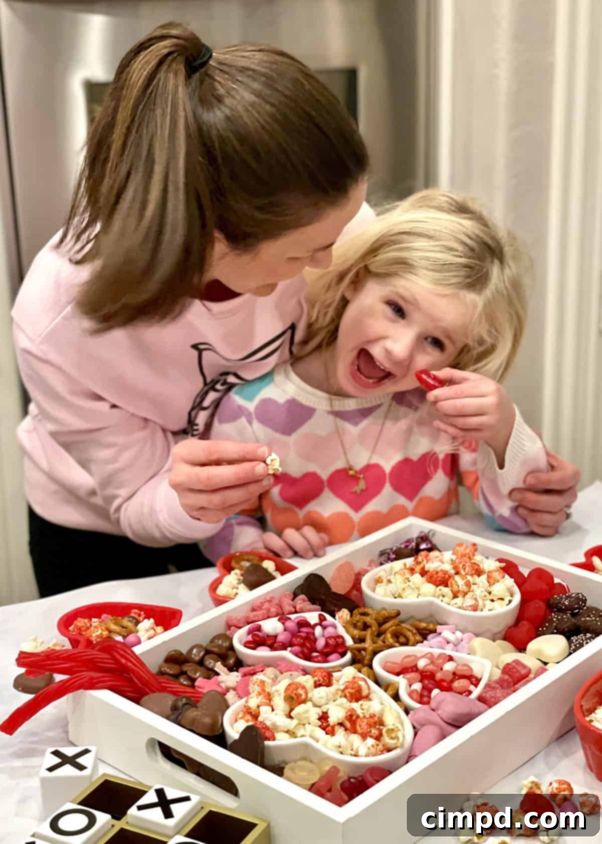 A close-up of hands reaching for treats on a Valentine's Day Movie Night Snack Board, emphasizing sharing and enjoyment.