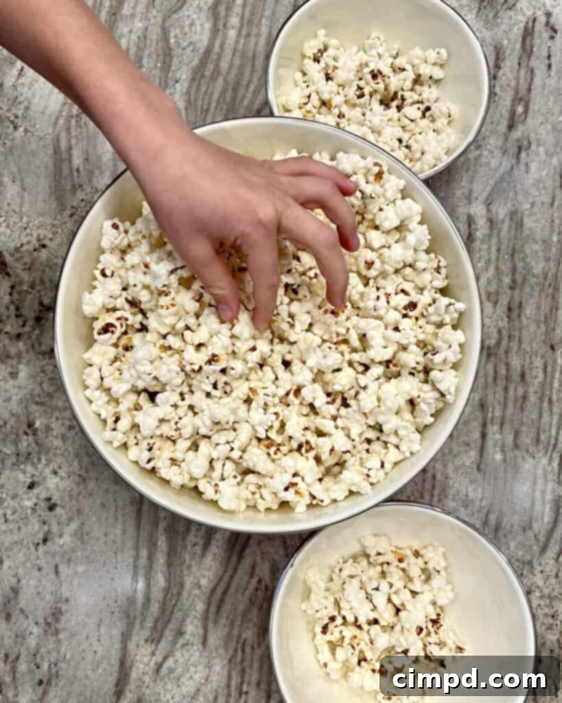Popcorn Perfection From Your Stovetop 6 A close-up shot of freshly popped stovetop popcorn in a large bowl, beautifully adorned with golden melted butter drizzled generously over the top.