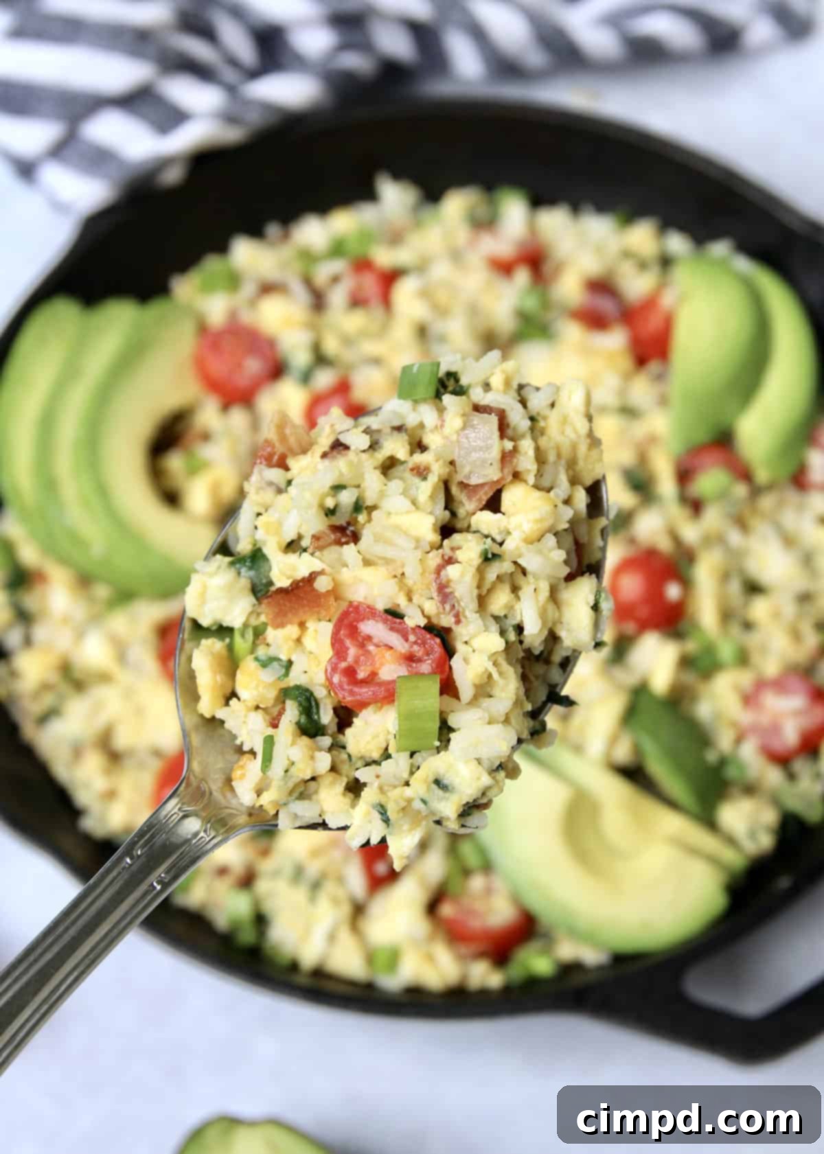 A serving of Breakfast Rice Scramble topped with fresh avocado and green onions.