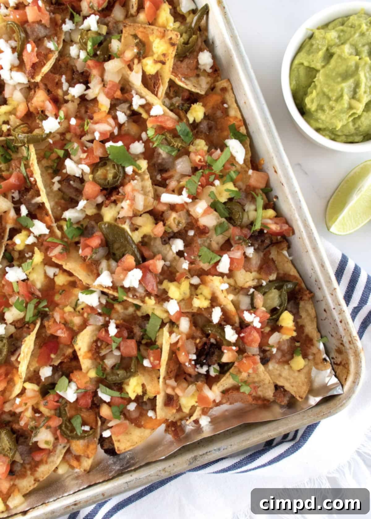 Rise and Shine Nachos 6 A beautifully arranged plate of breakfast nachos, garnished with fresh cilantro and lime wedges.