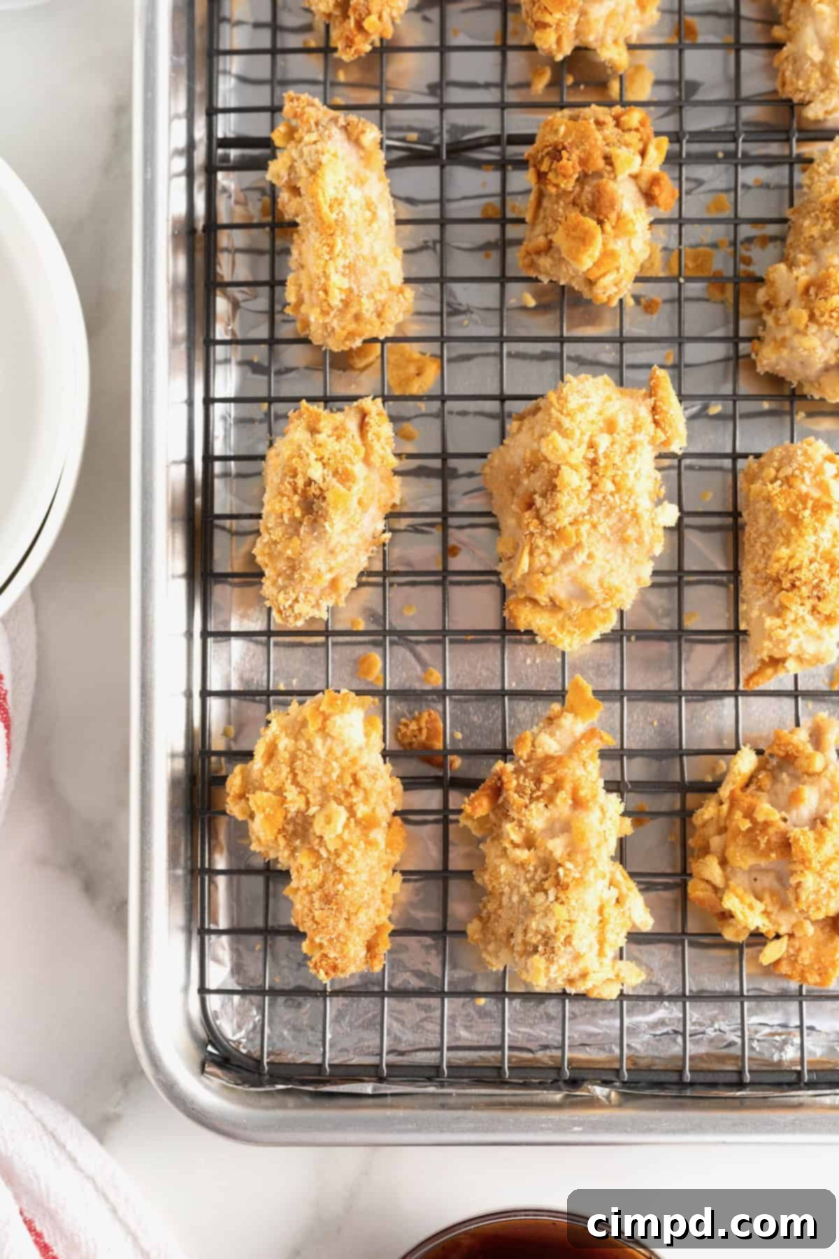 Baked chicken pieces coated in Ritz cracker crumbs, shown on a wire rack over a baking sheet, ready for storage or serving.