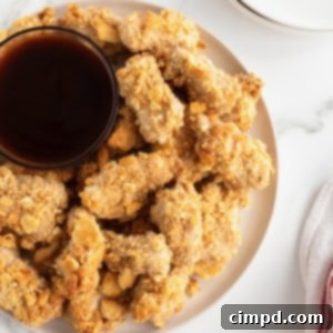 Crispy Ritzy Chicken Nuggets served on a white plate with barbecue sauce for dipping.