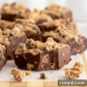 Several pieces of chocolate chip cookie fudge on a parchment lined surface.