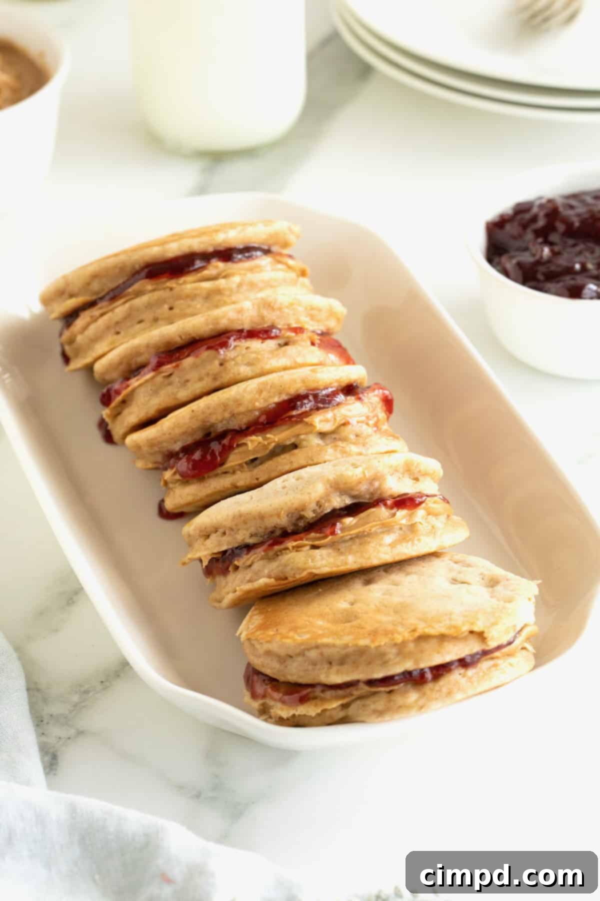Five pancake sandwiches in an oblong white serving dish.