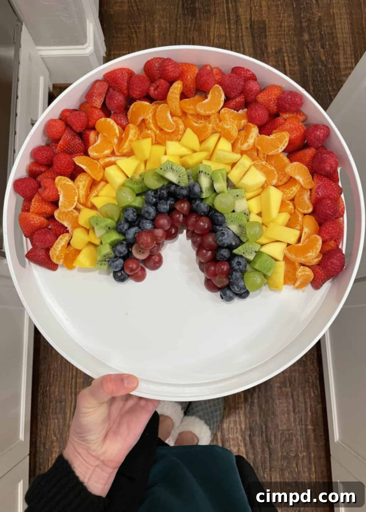 A close-up of the Rainbow Fruit Tray from the Unicorn Magic Birthday Spread, showing beautifully arranged strawberries, clementines, mangoes, kiwis, grapes, blueberries, and marshmallows forming a vibrant rainbow.