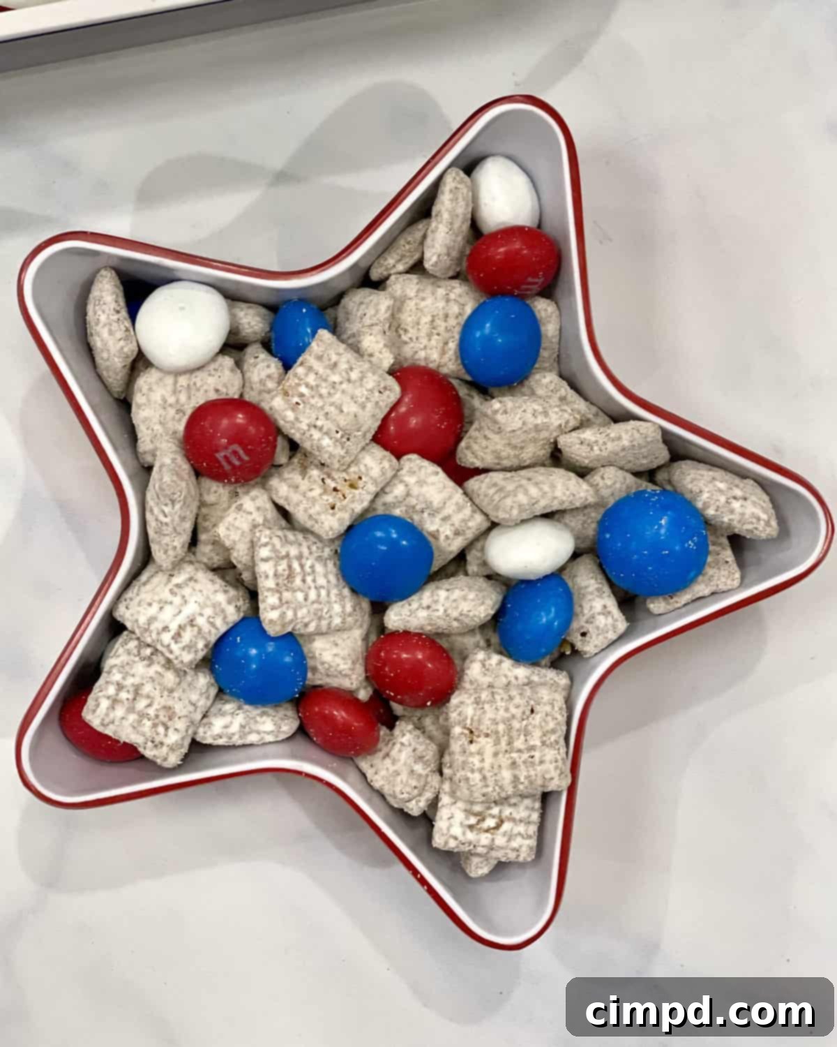 Patriotic Fourth of July S'mores Board 4 Close-up of a snack mix made with muddy buddies, red, white and blue M&Ms, served in a charming red and white plastic star-shaped bowl.