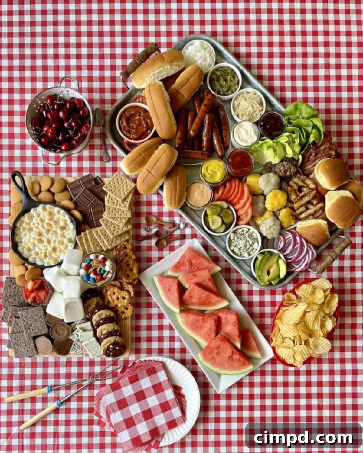 A vibrant summer cookout spread featuring grilled hot dogs, burgers, fresh fruits, and various toppings laid out on a table outdoors.