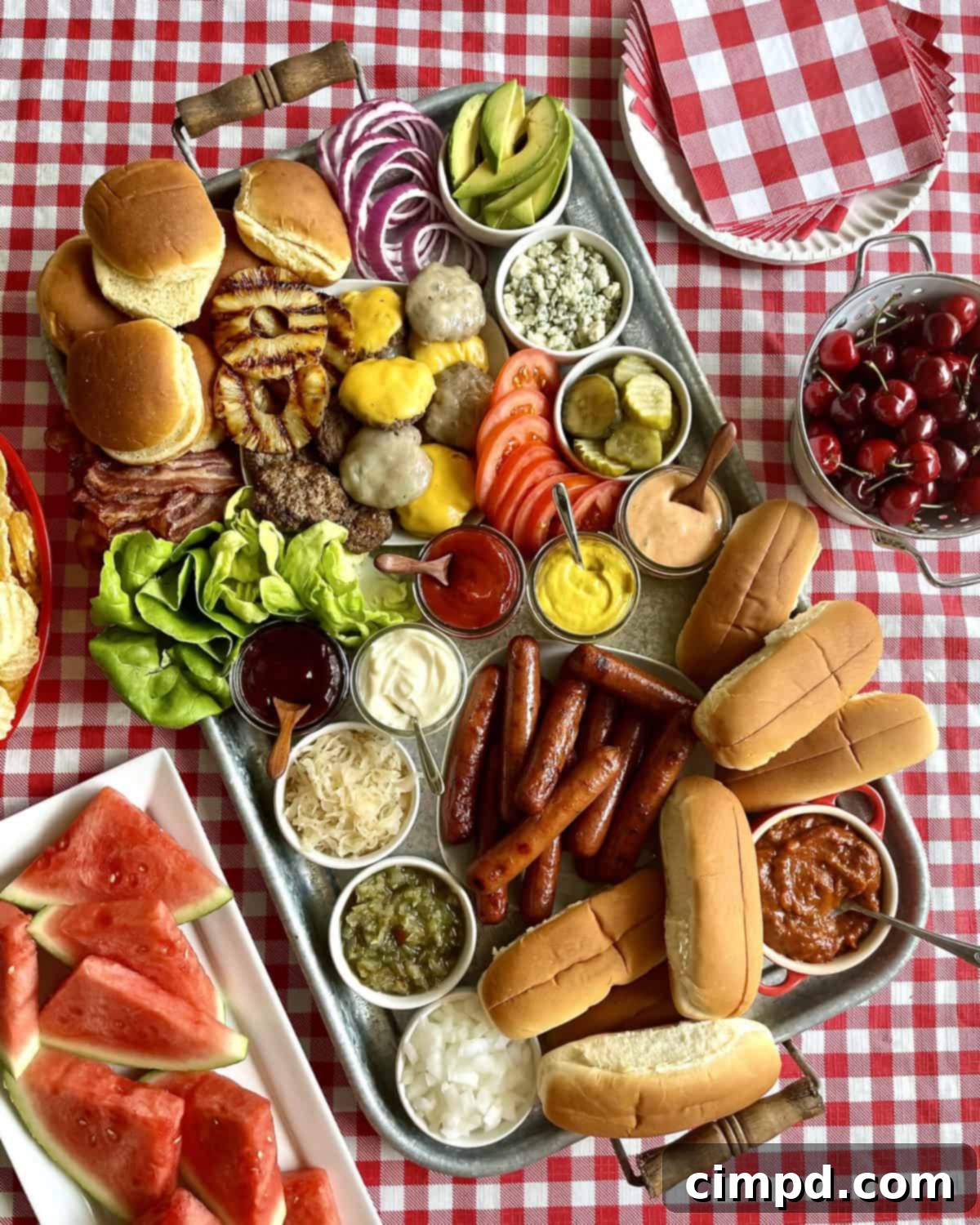 A beautifully presented build-your-own hot dog and burger board with grilled patties, hot dogs, chili, bacon, and a wide array of fresh toppings and buns.