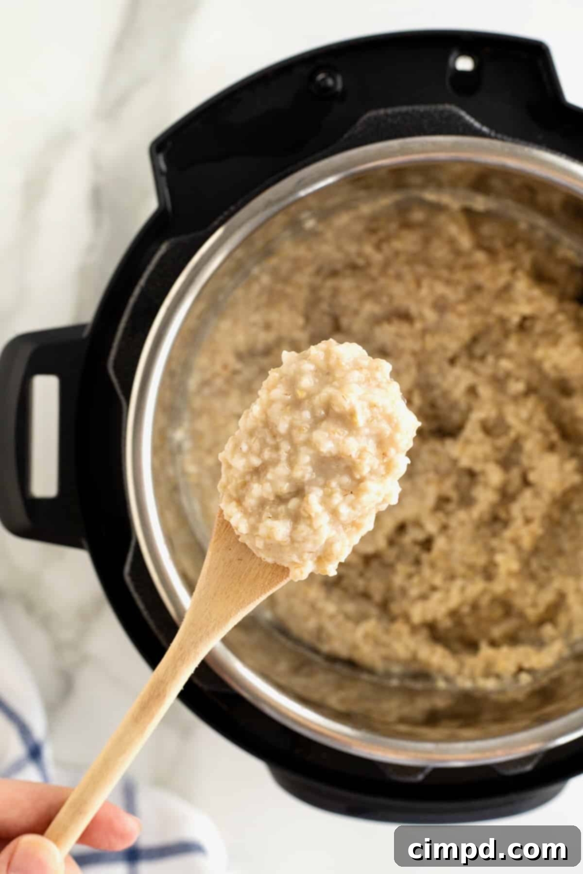 Perfect Steel Cut Oats Every Time 8 An open Instant Pot reveals perfectly cooked oatmeal, with a wooden spoonful of the creamy mixture poised above, ready to be enjoyed.
