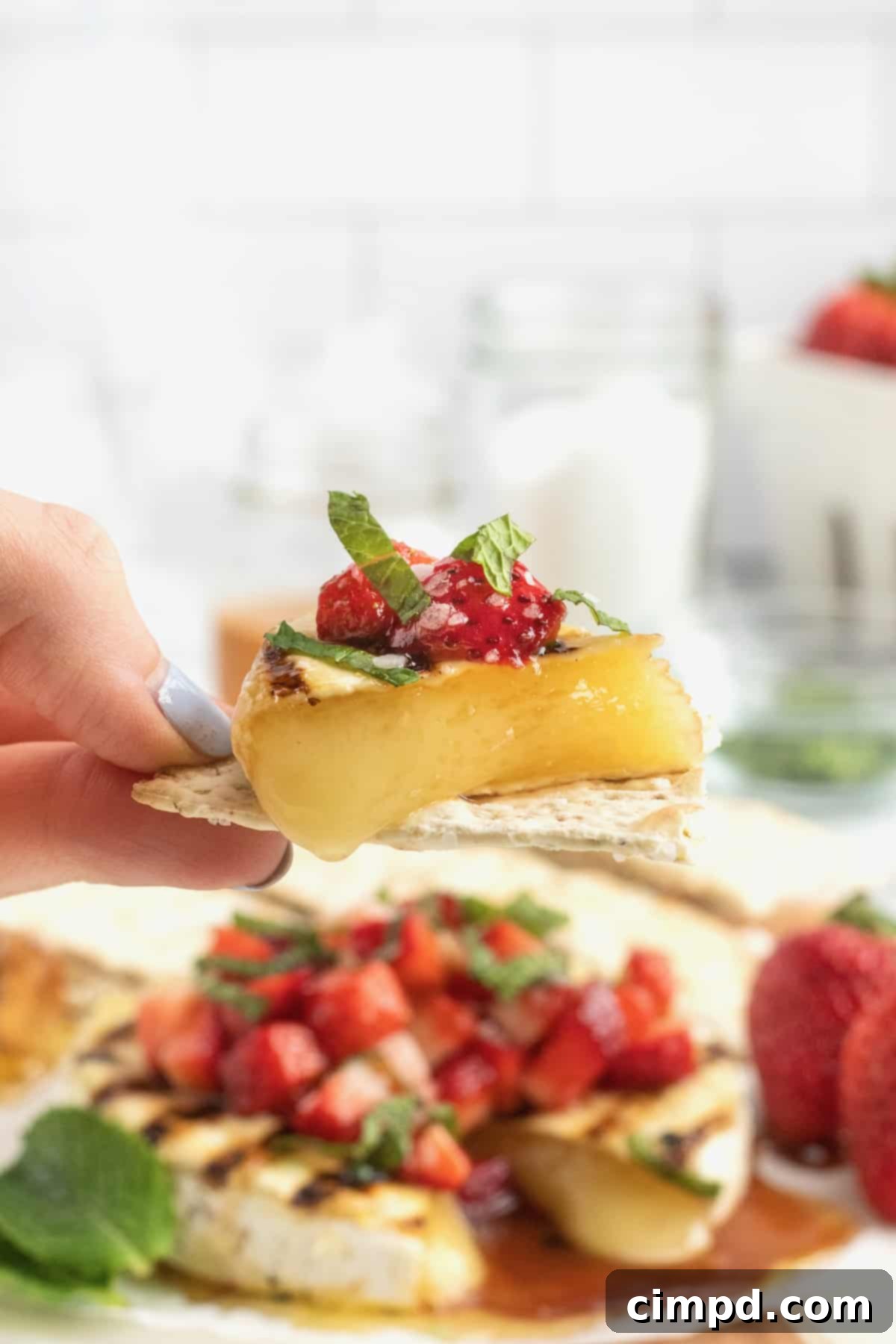 Closeup of creamy Grilled Brie with balsamic glazed strawberries and fresh mint