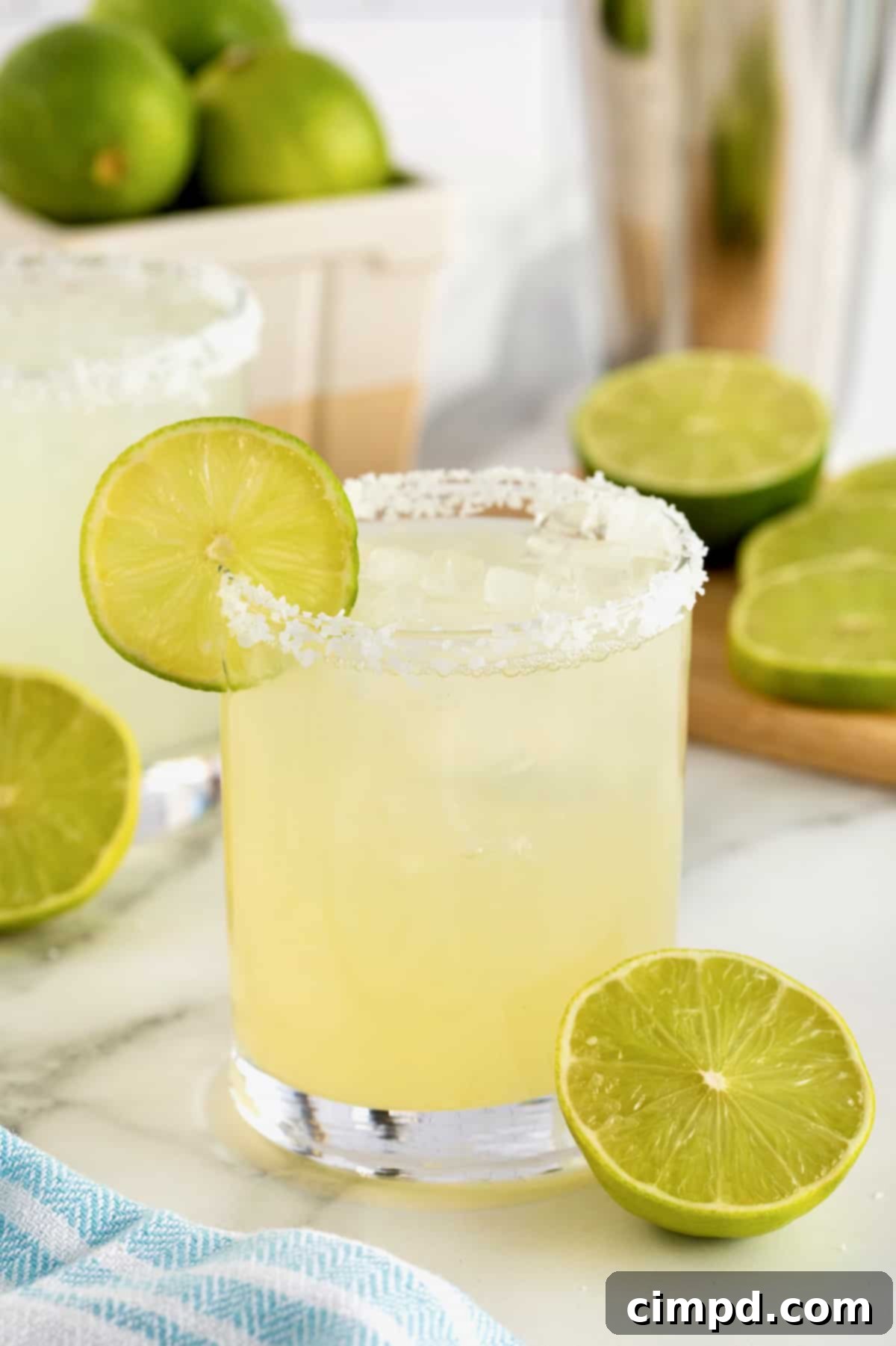 A salt rimmed glass filled with margarita on a white marble counter.