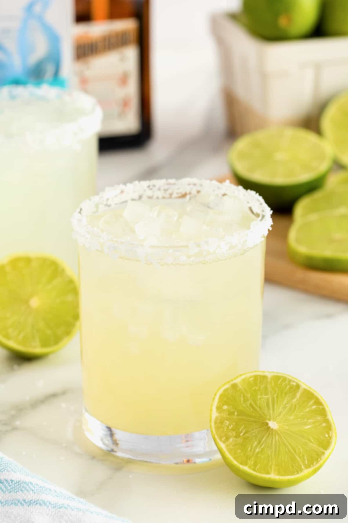 A salt rimmed glass filled with margarita on a white marble counter.