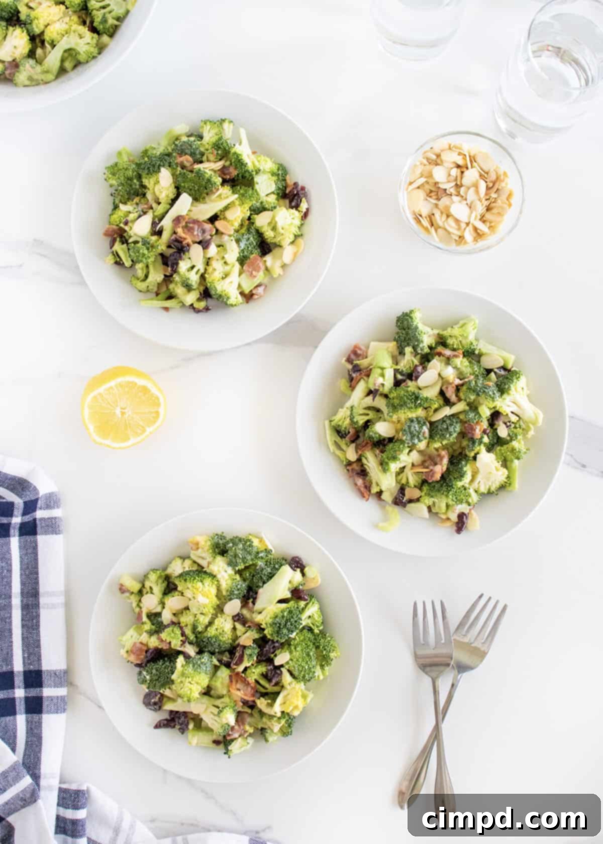 Three individual white salad plates each with a generous serving of creamy broccoli salad.