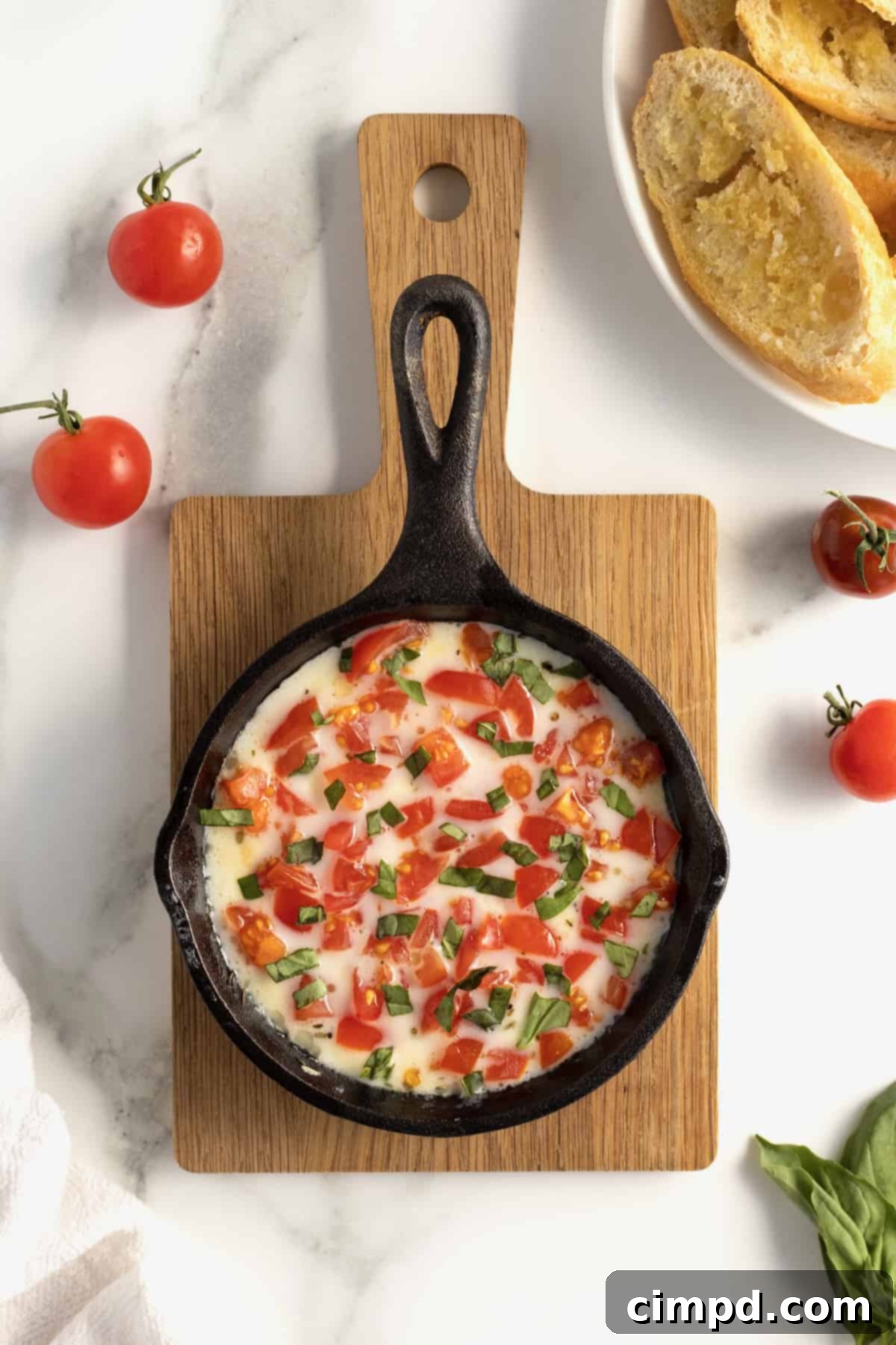 Bubbly Baked Caprese Dip 4 Serving Skillet Caprese Dip with crostini on a rustic wooden board