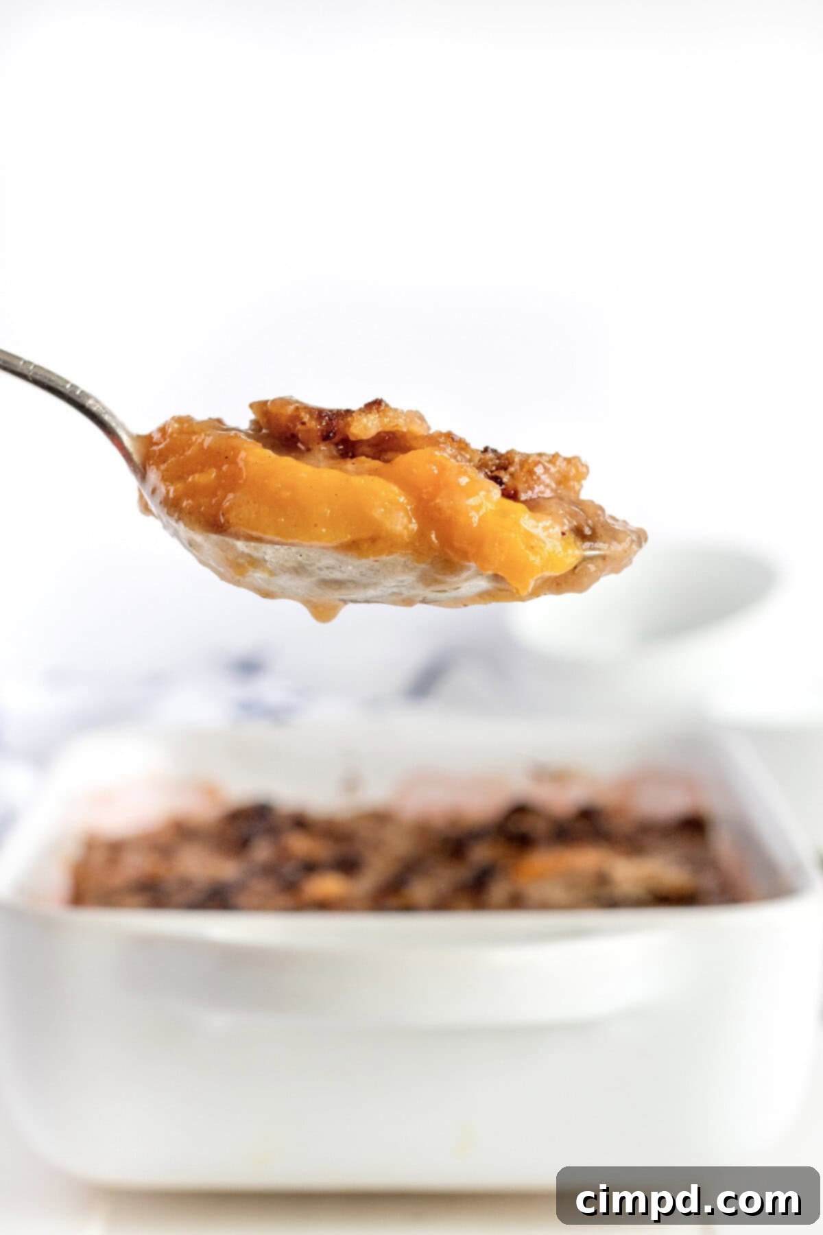 A serving of peach crumble on a metal serving spoon.