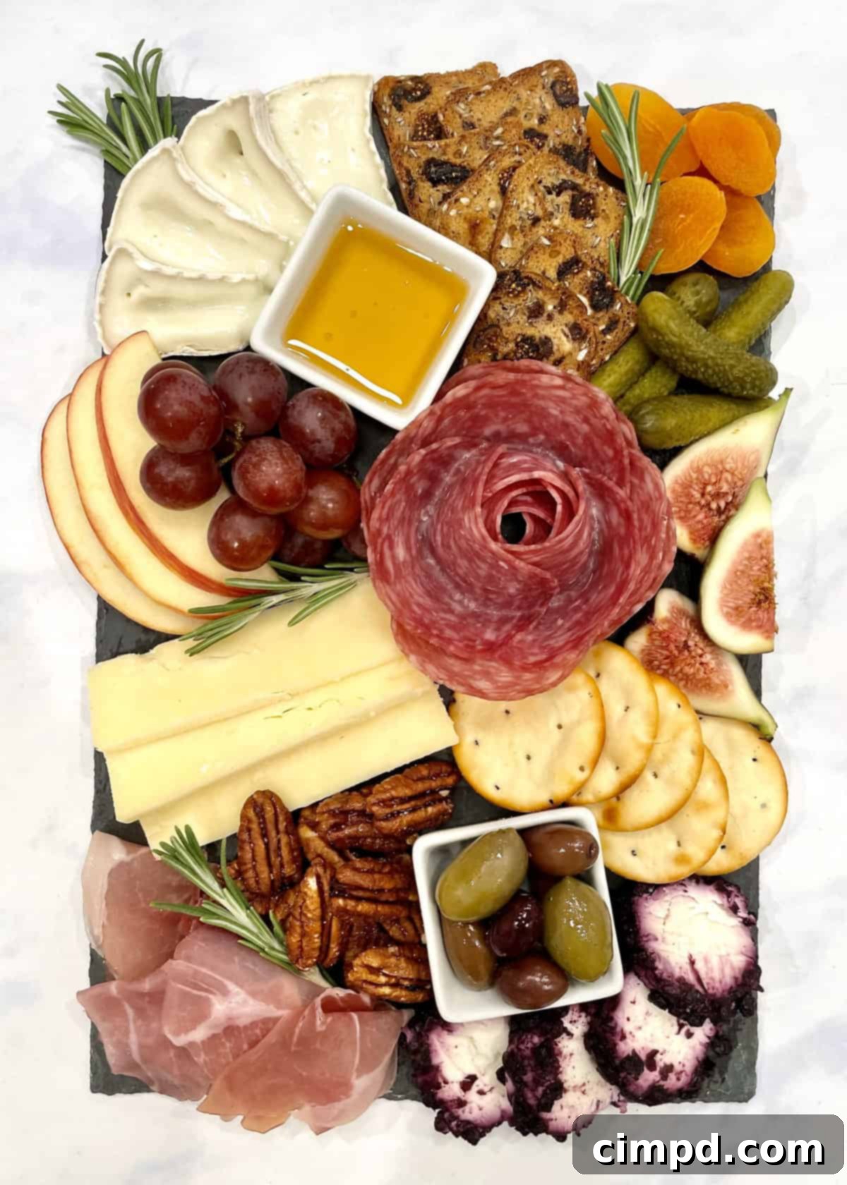 A small wooden board with an array of premium meats, artisanal cheeses, crisp apple slices, sweet red grapes, a vibrant assortment of olives, and various gourmet crackers, all artfully arranged for a sophisticated mini charcuterie experience.