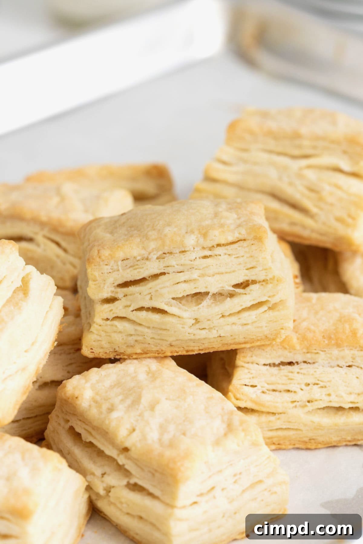 Comforting Buttermilk Biscuits 6 A freshly baked pile of golden homestyle buttermilk biscuits, still warm from the oven, resting on a clean white kitchen surface.