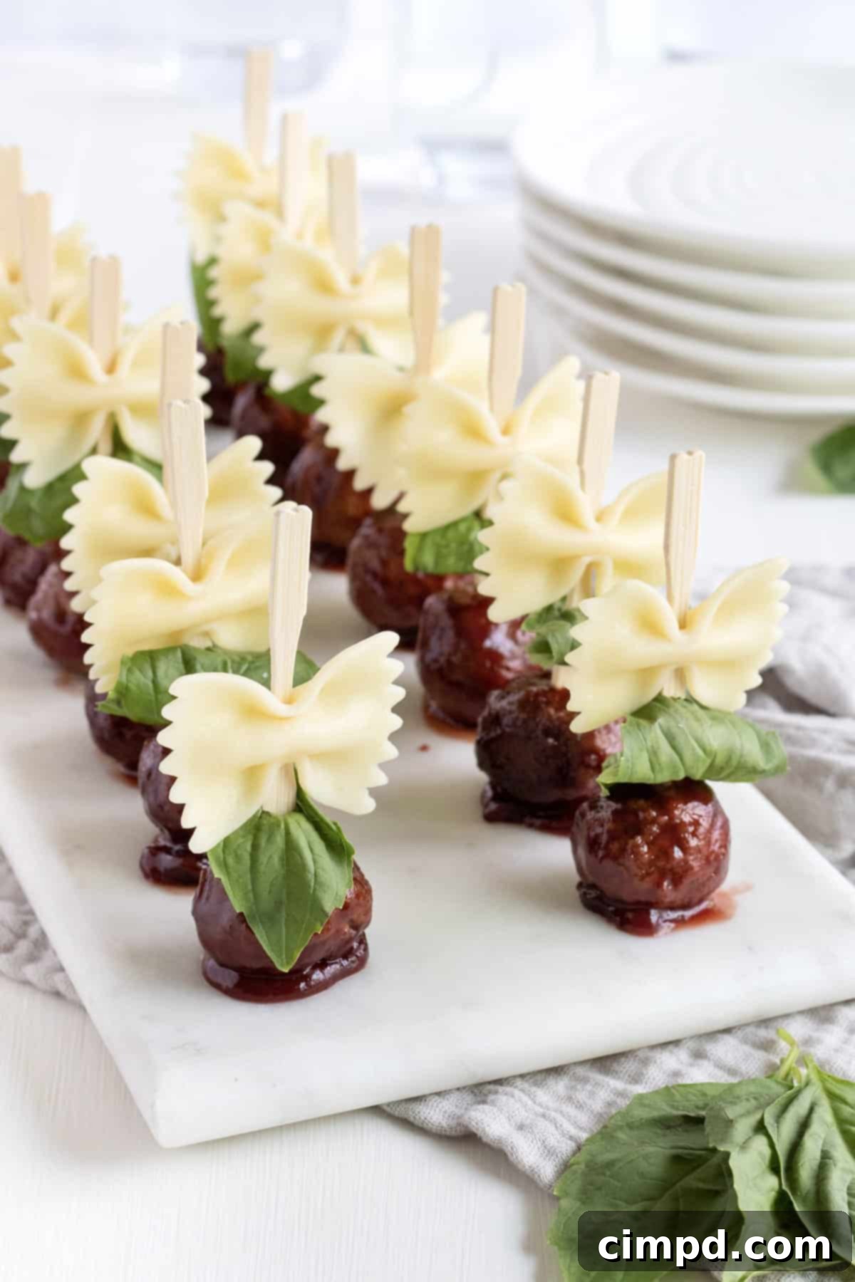 A stunning arrangement of Bowtie Pasta and Meatball Skewers by The BakerMama, beautifully presented on a serving tray. Each skewer showcases a perfect harmony of ingredients, ready to be enjoyed as a gourmet appetizer.