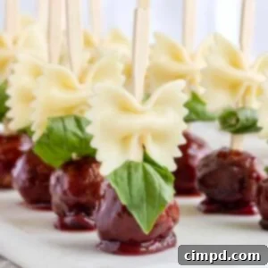 A top-down view of perfectly arranged Bowtie Pasta and Cocktail Meatball Skewers by The BakerMama on a wooden serving board, showcasing the vibrant colors and appealing presentation of this delightful appetizer.