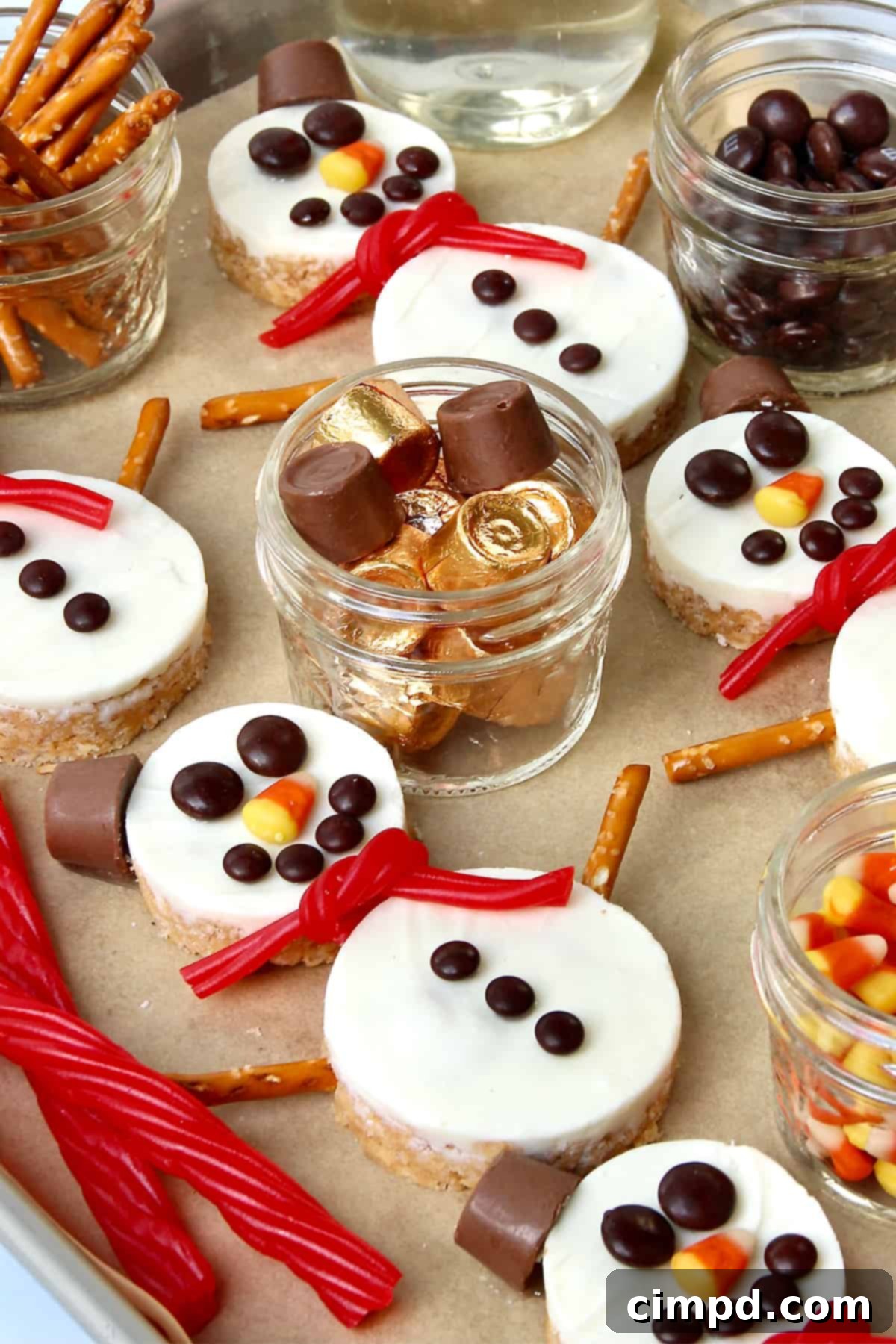 Festive Hot Chocolate Board and Snowman Scotcheroos 3 Close-up view of multiple adorable Snowman Scotcheroos, showcasing their intricate details like pretzel arms, candy buttons, and licorice scarves, ready to be enjoyed.