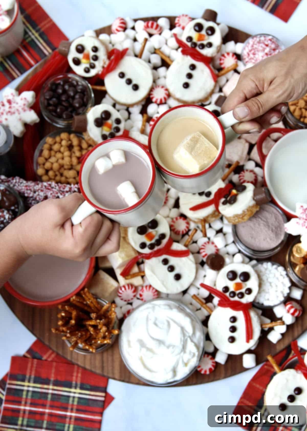 Festive Hot Chocolate Board and Snowman Scotcheroos 9 A person's hand holding a steaming mug of hot chocolate, garnished with festive toppings, taken from the hot chocolate board.