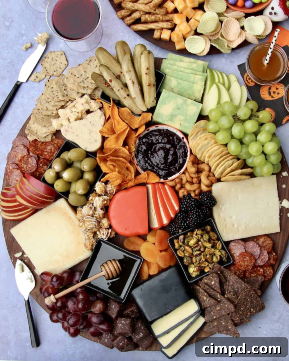 A beautifully arranged Halloween Cheese Board featuring themed cheeses, fruits, nuts, and spooky decor, by The BakerMama.