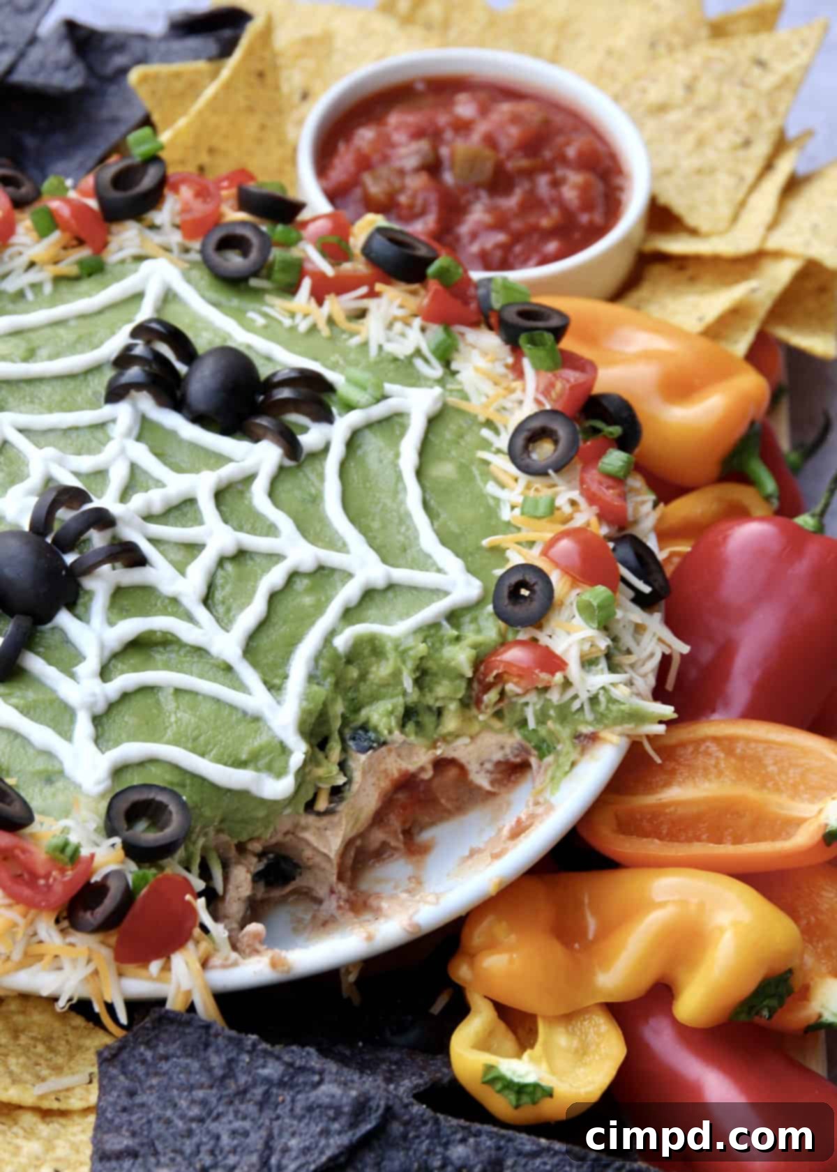 Spider Web Seven Layer Dip by The BakerMama - Close-up of the seven-layer dip with a sour cream spiderweb and olive spiders.