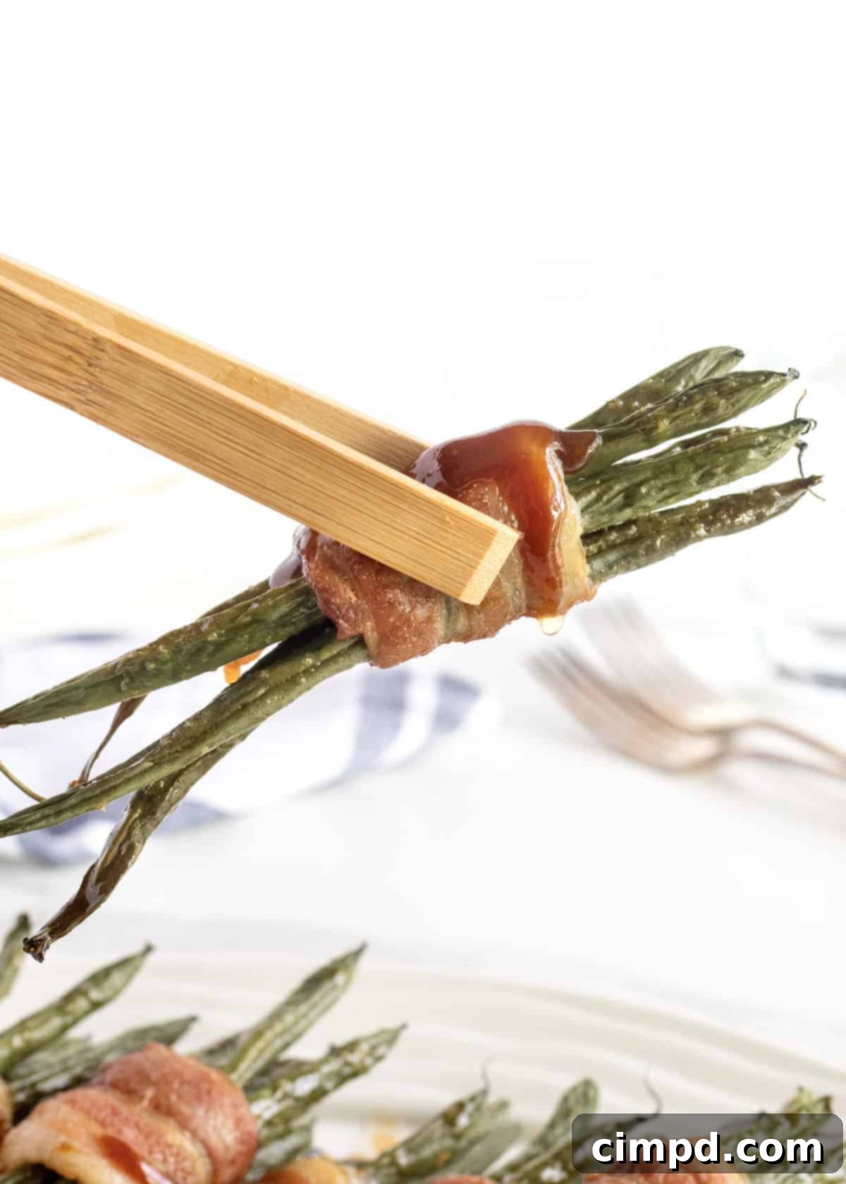 Close-up of Green Bean Bundles cooking in a casserole dish, bacon turning golden.