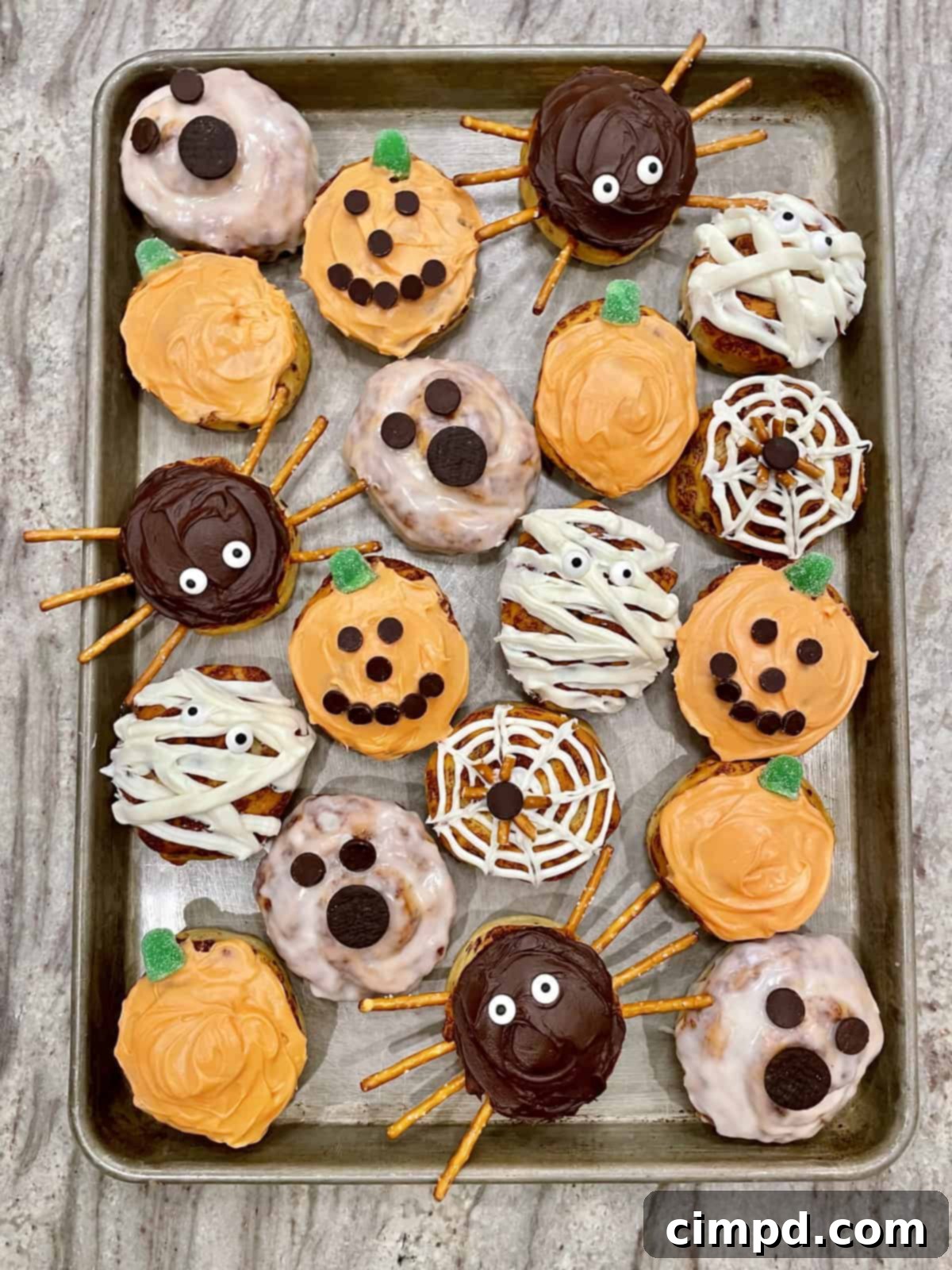 A plate of Halloween themed cinnamon rolls including a pumpkin, ghost, and spider design.