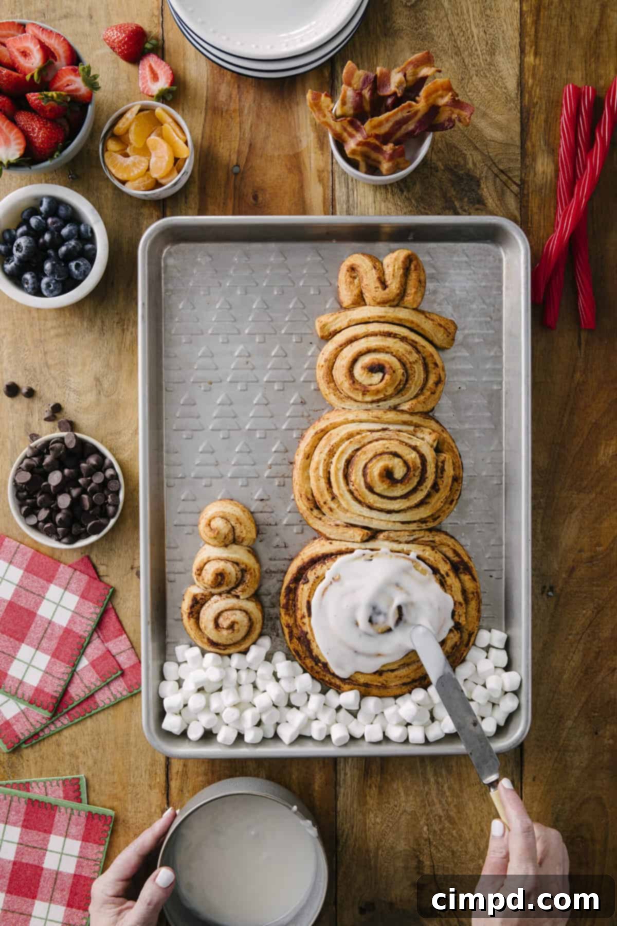 Frosty Cinnamon Creations 5 Baked Cinnamon Roll Snowmen freshly iced and ready for decoration, creating a sweet and festive holiday breakfast. Recipe by The BakerMama