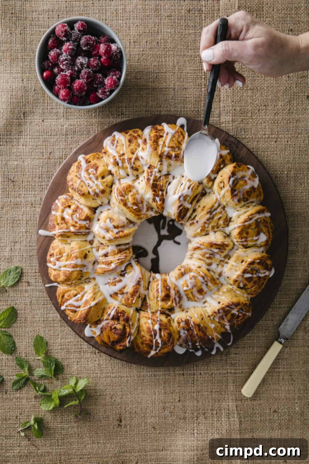 Beautifully decorated Cinnamon Roll Wreath, ready for holiday serving, with sugared cranberries and mint leaves.