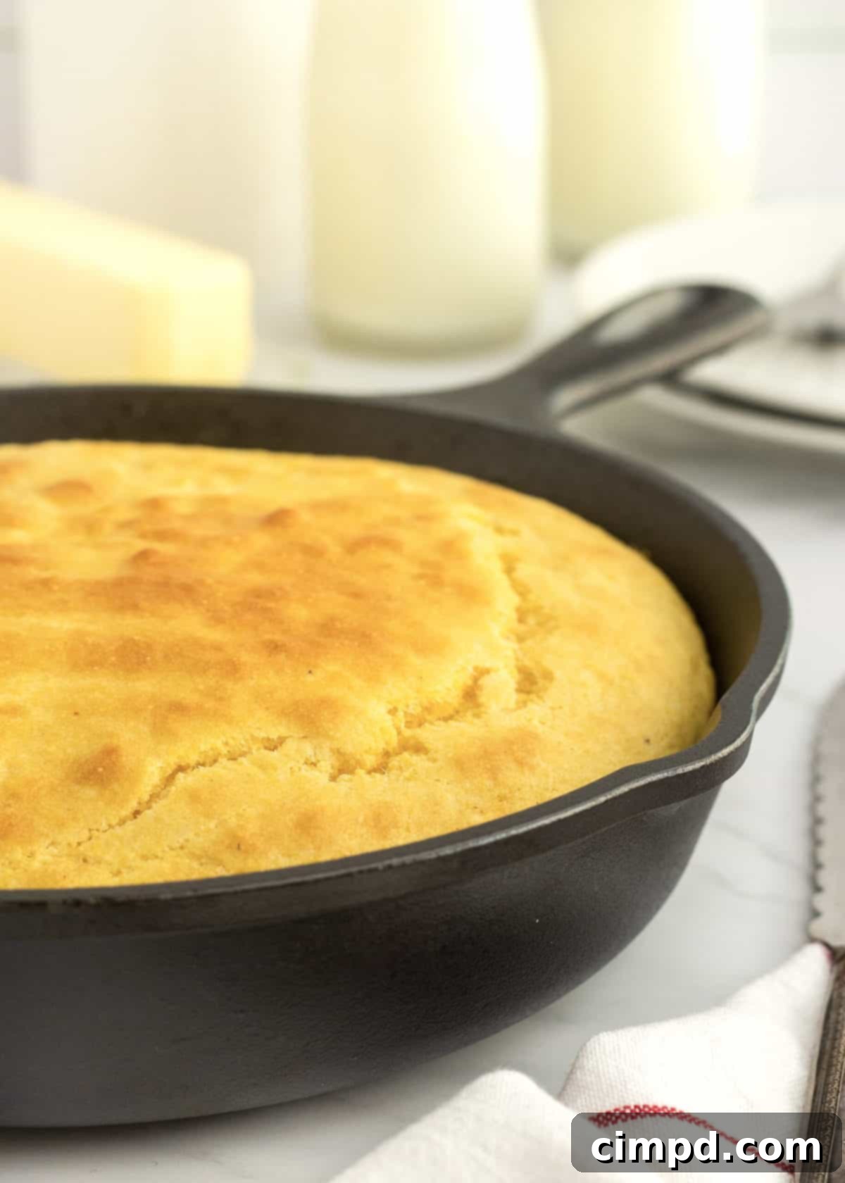 A cast iron skillet of cornbread on a white marble counter. 